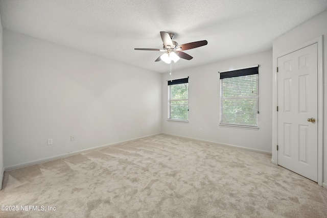 empty room featuring ceiling fan, light carpet, and baseboards