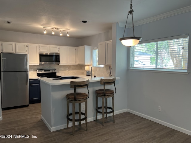 kitchen with a breakfast bar, appliances with stainless steel finishes, white cabinetry, decorative light fixtures, and kitchen peninsula