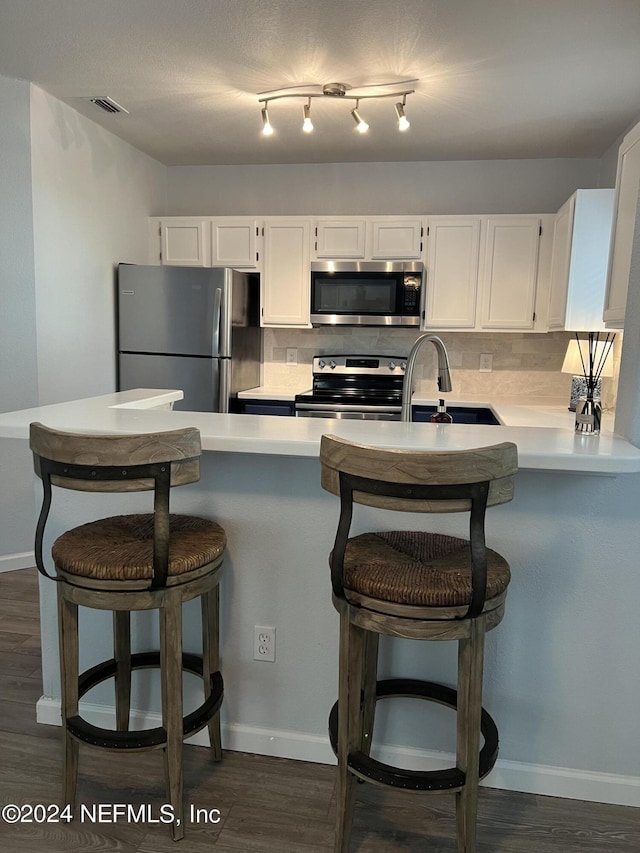 kitchen featuring white cabinetry, a kitchen breakfast bar, kitchen peninsula, and appliances with stainless steel finishes