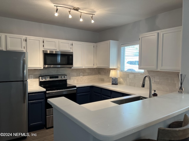 kitchen featuring sink, white cabinetry, stainless steel appliances, decorative backsplash, and kitchen peninsula