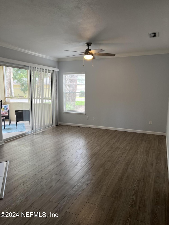 empty room featuring crown molding, dark wood-type flooring, and ceiling fan