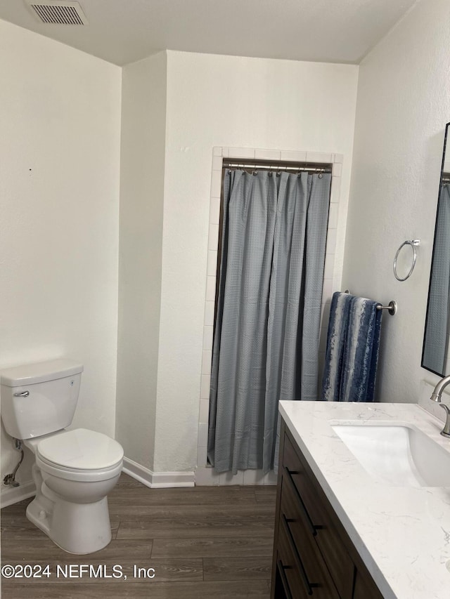 bathroom with walk in shower, vanity, toilet, and hardwood / wood-style floors