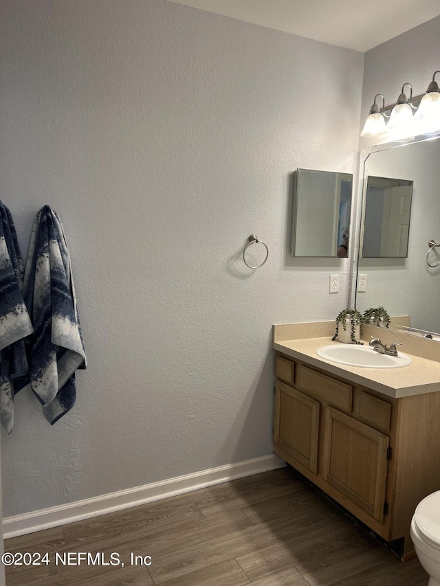 bathroom featuring wood-type flooring, toilet, and vanity