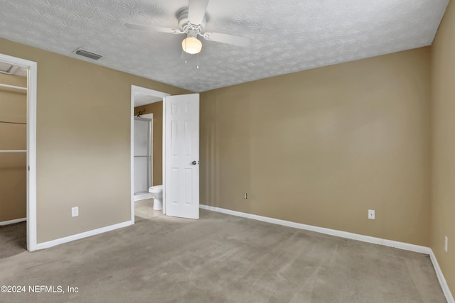 unfurnished bedroom featuring connected bathroom, a spacious closet, ceiling fan, light carpet, and a closet