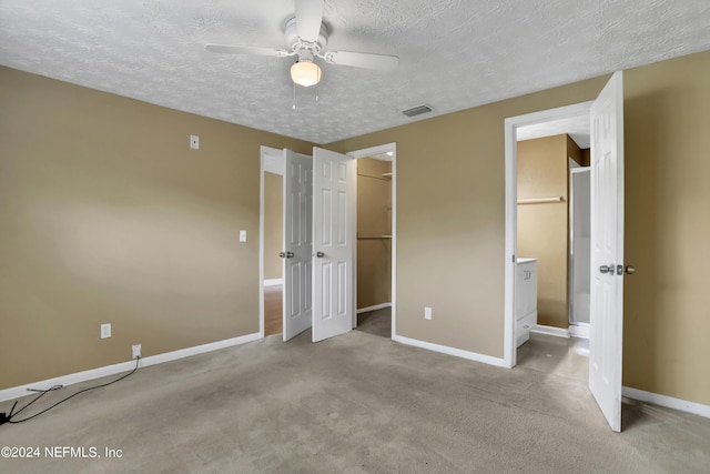 unfurnished bedroom featuring a spacious closet, light colored carpet, ceiling fan, and a closet