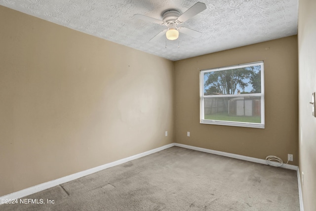 carpeted empty room with ceiling fan and a textured ceiling