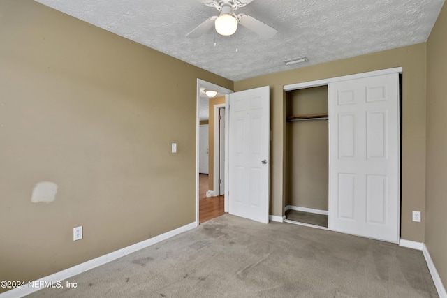 unfurnished bedroom with light carpet, a textured ceiling, a closet, and ceiling fan