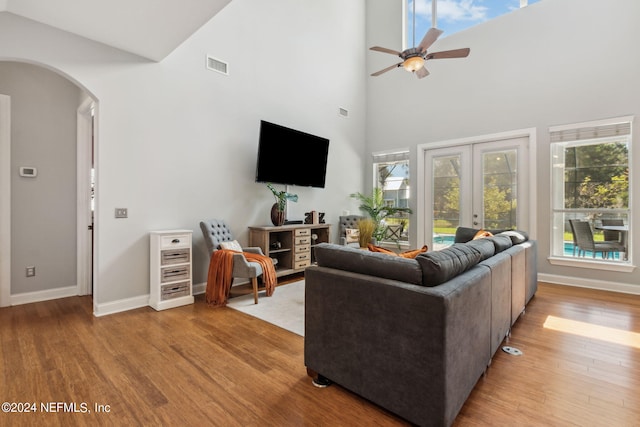 living room with light hardwood / wood-style floors, french doors, ceiling fan, and a high ceiling