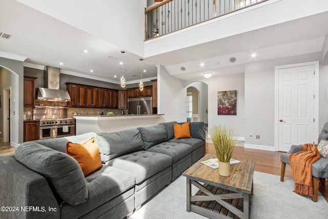 living room with ornamental molding, a towering ceiling, and light hardwood / wood-style flooring