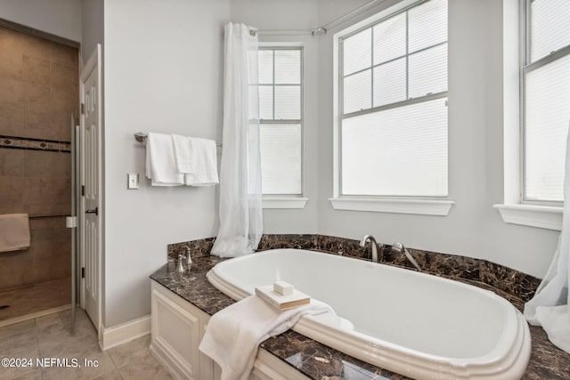 bathroom with a relaxing tiled tub and tile patterned floors