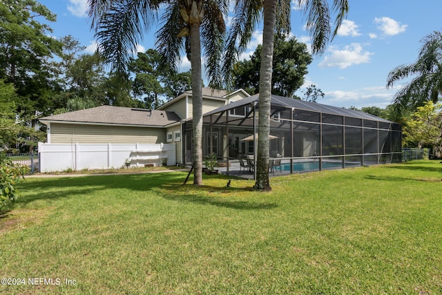 back of property with a fenced in pool, a lanai, and a lawn