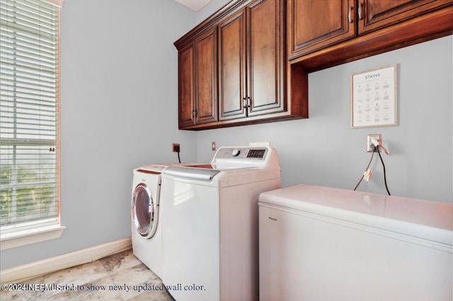 clothes washing area with cabinets and washing machine and clothes dryer