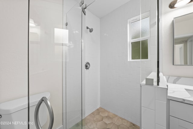 bathroom featuring vanity, a tile shower, and toilet