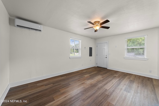 unfurnished room with electric panel, an AC wall unit, wood-type flooring, and ceiling fan