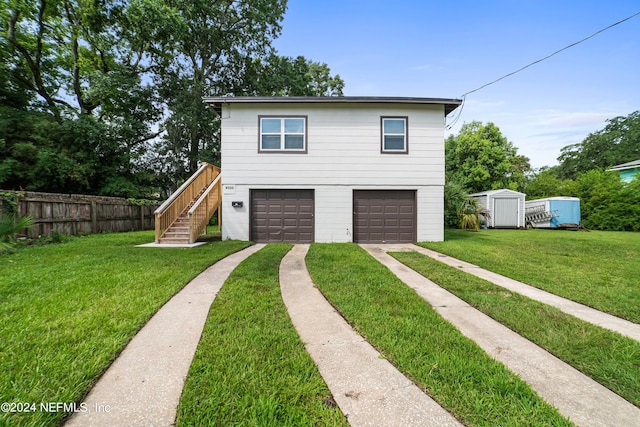 front of property featuring a storage unit, a garage, and a front lawn