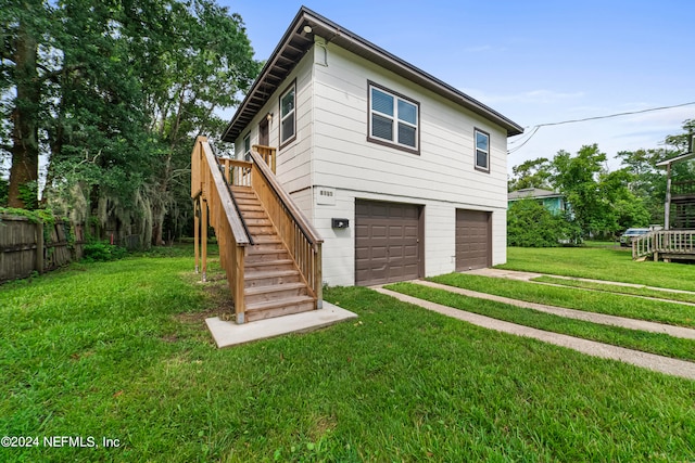 back of house featuring a garage, a lawn, and a deck