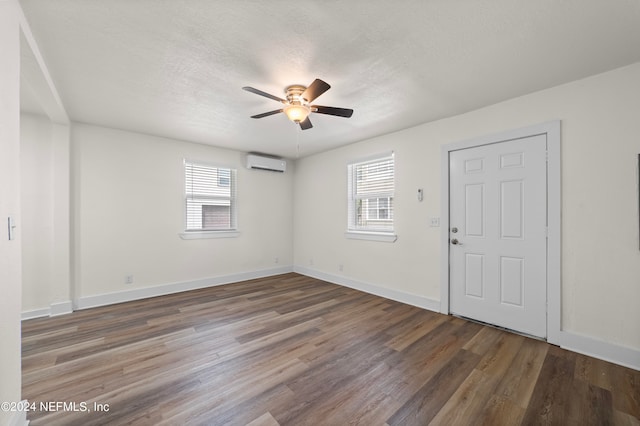 foyer entrance featuring a wall mounted air conditioner, hardwood / wood-style floors, and ceiling fan