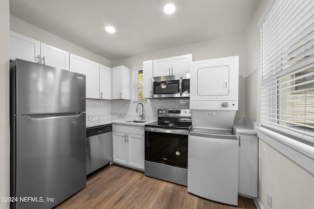 kitchen with appliances with stainless steel finishes, dark hardwood / wood-style flooring, white cabinets, and sink