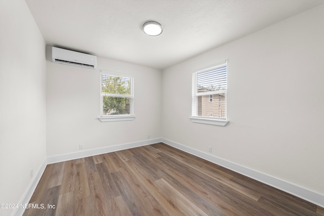 empty room with a wall mounted AC and hardwood / wood-style flooring