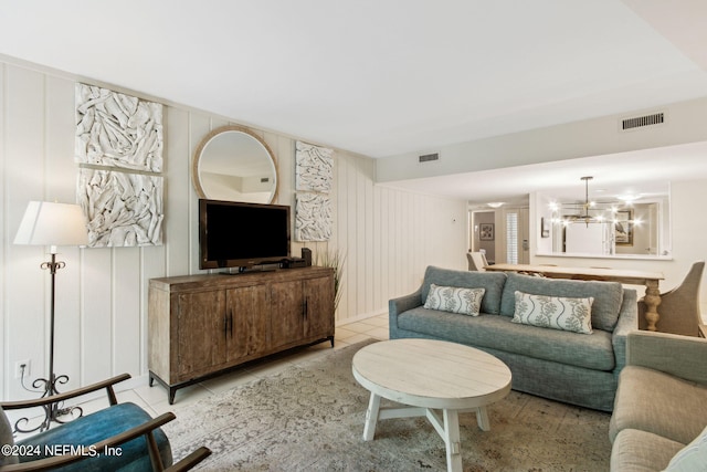 tiled living room featuring an inviting chandelier and wooden walls