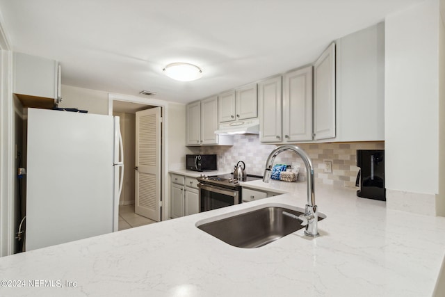 kitchen featuring sink, white refrigerator, stainless steel electric range oven, light stone counters, and decorative backsplash