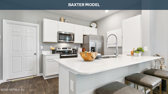kitchen featuring dark wood-type flooring, a sink, stainless steel appliances, a breakfast bar area, and white cabinets