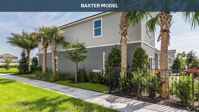 view of property exterior featuring a yard, fence, and stucco siding