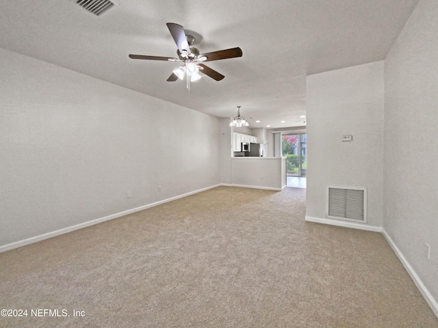 empty room with ceiling fan with notable chandelier and light carpet