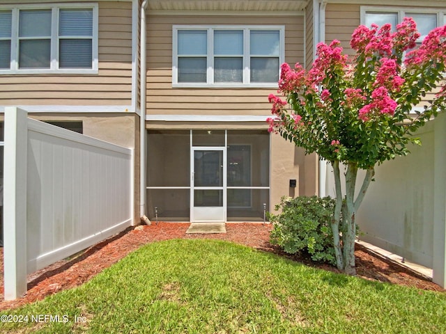 rear view of property with a lawn and a sunroom