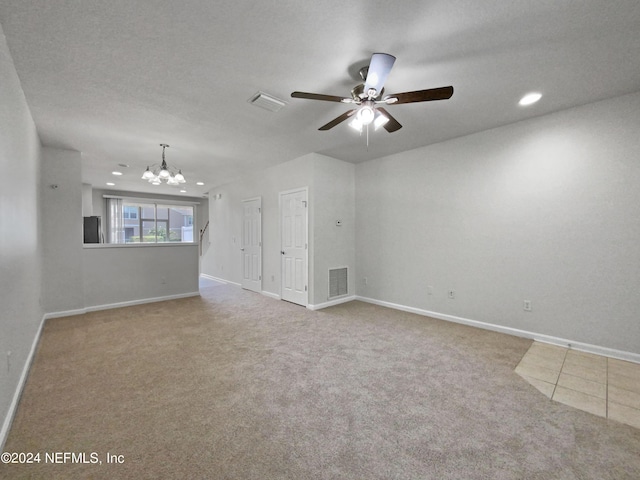 carpeted spare room featuring ceiling fan with notable chandelier and a textured ceiling