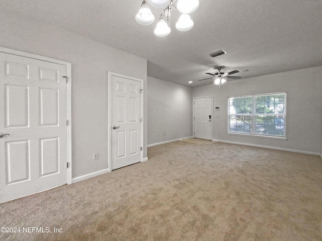 spare room featuring ceiling fan with notable chandelier, carpet floors, and a textured ceiling