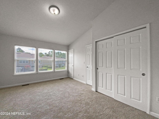 unfurnished bedroom with lofted ceiling, carpet flooring, and a textured ceiling