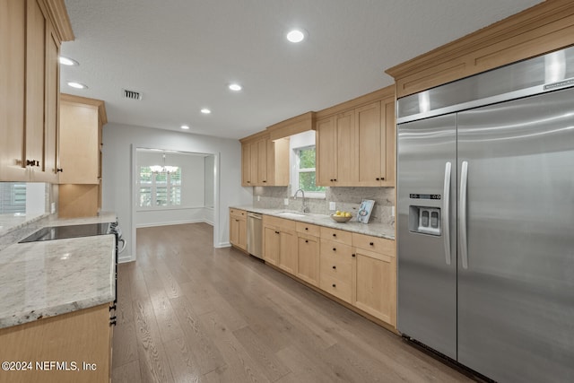 kitchen featuring light hardwood / wood-style flooring, sink, appliances with stainless steel finishes, light brown cabinetry, and light stone counters