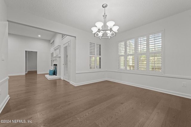 unfurnished dining area featuring dark hardwood / wood-style flooring, a chandelier, and a textured ceiling