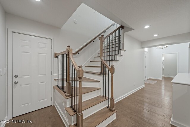 stairs featuring a chandelier and hardwood / wood-style flooring