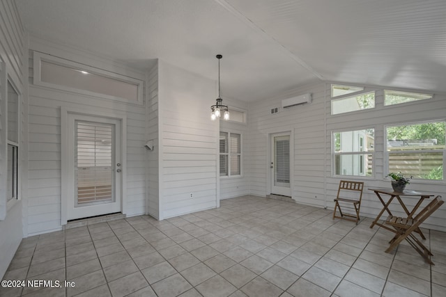 unfurnished sunroom featuring a chandelier, vaulted ceiling, and a wall mounted AC