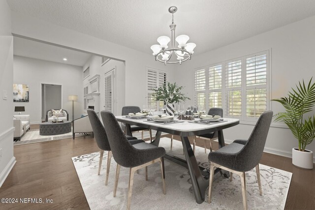 dining space with a chandelier, a textured ceiling, and dark hardwood / wood-style floors