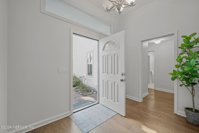 foyer entrance with light wood-type flooring and an inviting chandelier