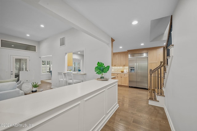 kitchen with stainless steel built in refrigerator, light brown cabinets, and light wood-type flooring