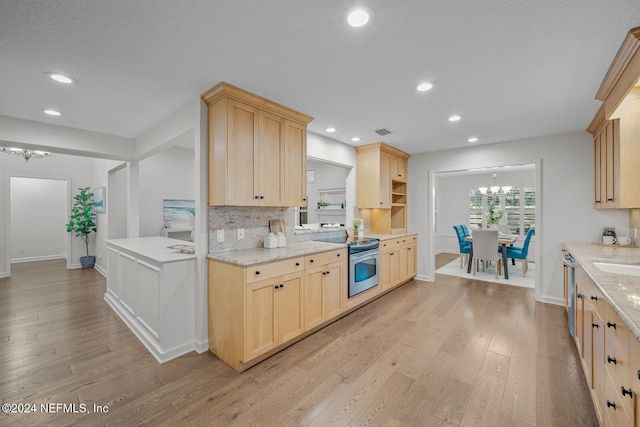 kitchen with a chandelier, appliances with stainless steel finishes, light wood-type flooring, and light brown cabinetry