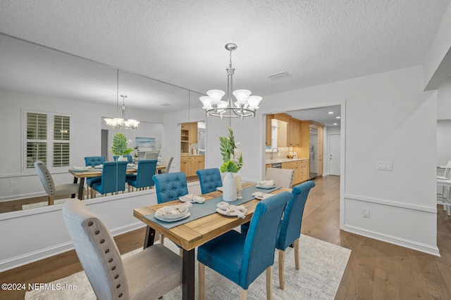 dining area featuring a textured ceiling, hardwood / wood-style flooring, an inviting chandelier, and sink