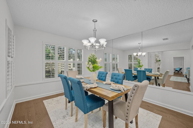 dining room featuring a chandelier, a textured ceiling, and dark wood-type flooring