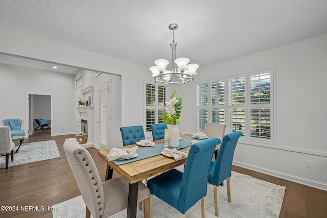 dining area with a textured ceiling, dark wood-type flooring, and a notable chandelier