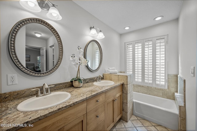 bathroom featuring a washtub, a textured ceiling, and vanity