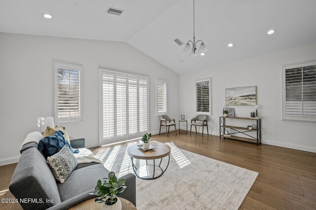 living room with a notable chandelier, dark wood-type flooring, and lofted ceiling