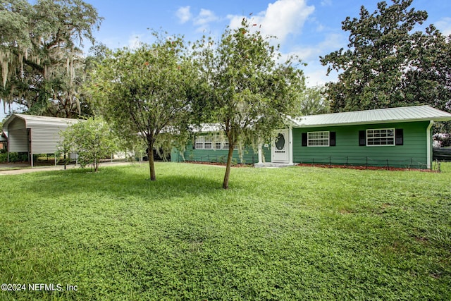 view of front of property with a detached carport, metal roof, and a front yard