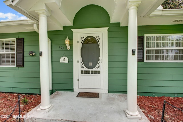 view of exterior entry with covered porch and visible vents