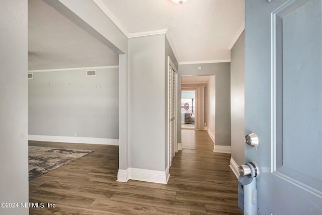 corridor with baseboards, visible vents, ornamental molding, wood finished floors, and a textured ceiling