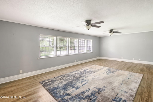 spare room featuring a textured ceiling, wood finished floors, a ceiling fan, baseboards, and ornamental molding