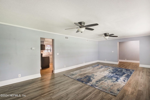 empty room featuring visible vents, ornamental molding, a textured ceiling, wood finished floors, and baseboards